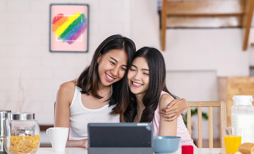 LGBTQ+ couple watching videos from Access Video On Demand on their laptop at home