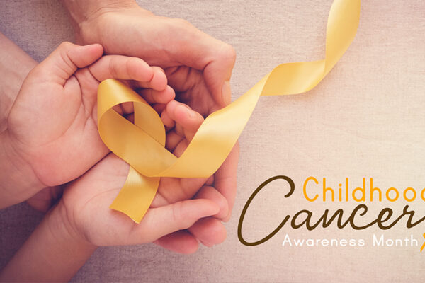Yellow ribbon, representing childhood cancer awareness, in a child's and adult's cupped hands