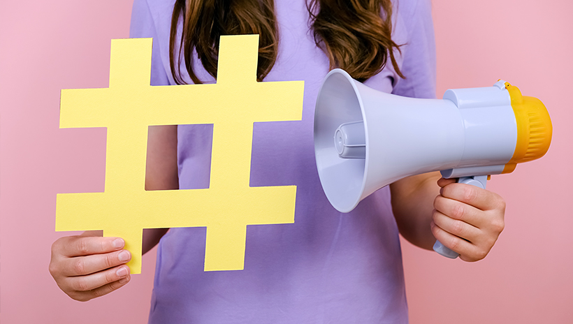 Woman holding a giant hashtag next to a megaphone