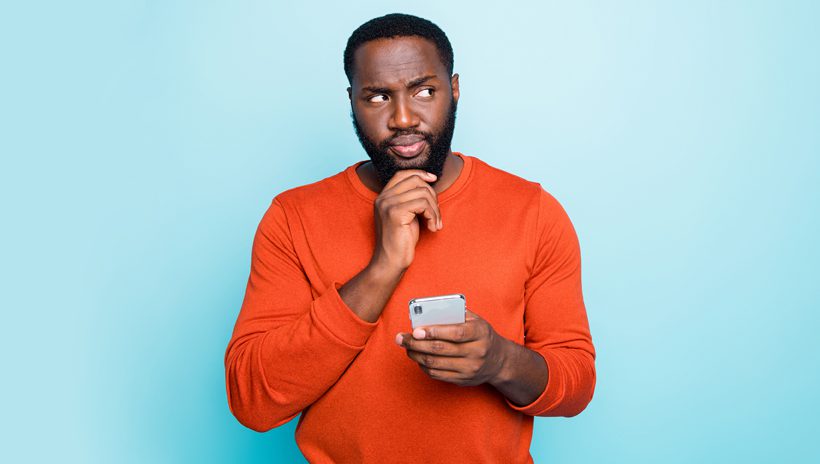 Man with doubtful expression as he reads news on his phone
