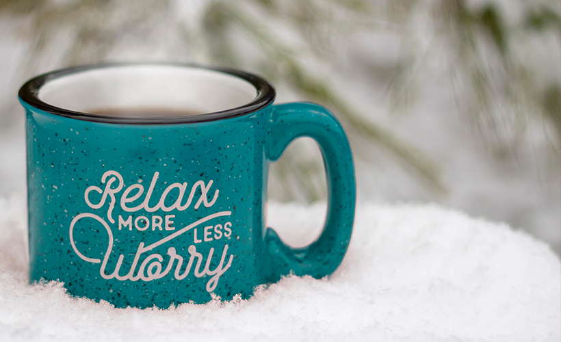 Mug with "Relax More, Worry Less" in a snowbank