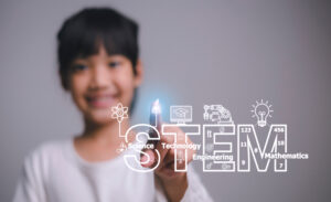 Elementary student lighting a sign that says "STEM"