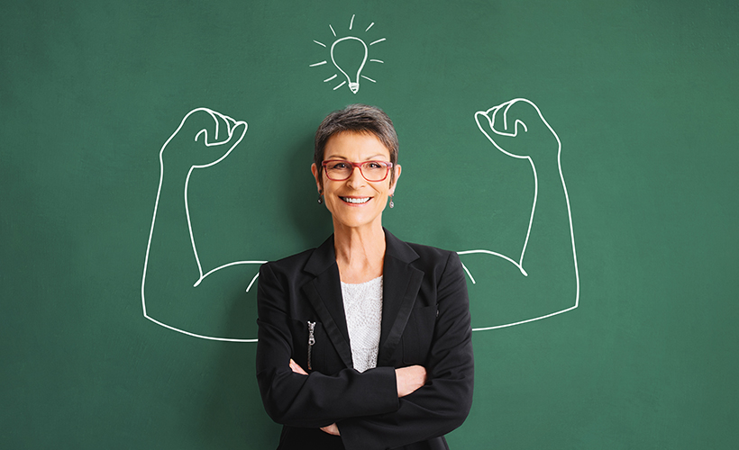 Empowered teacher standing against chalkboard with strong arms drawn on it