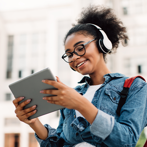 College student with headphones on and looking at tablet