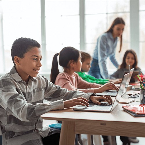 Kids in a classroom looking at laptops