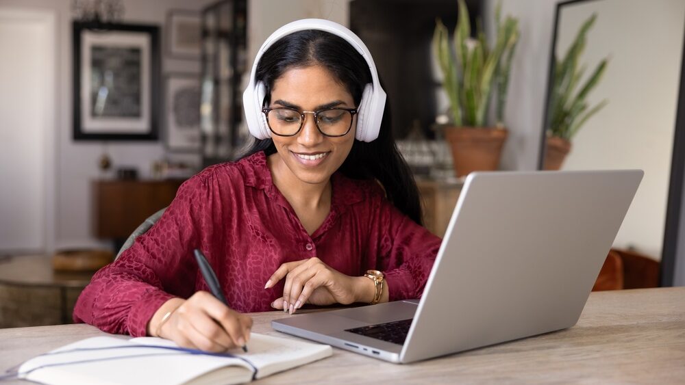 Woman in glasses and wireless headphones, writing